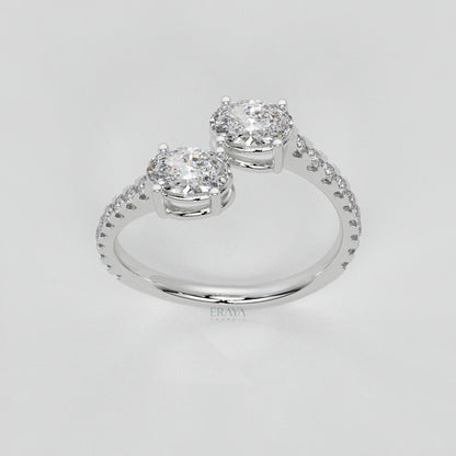 Silver ring with two prominent diamonds on a light gray background