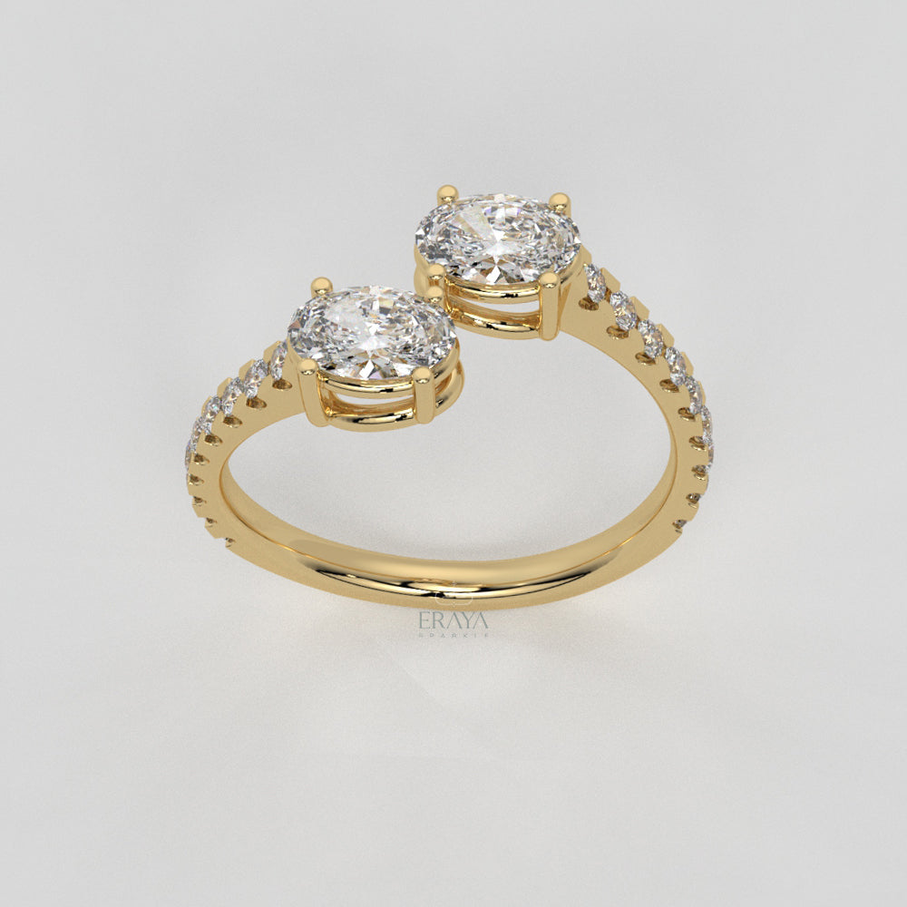 Gold ring with two large diamonds and smaller diamonds on a light gray background