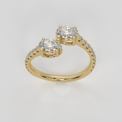 Gold ring with two large diamonds and smaller diamonds on a light gray background