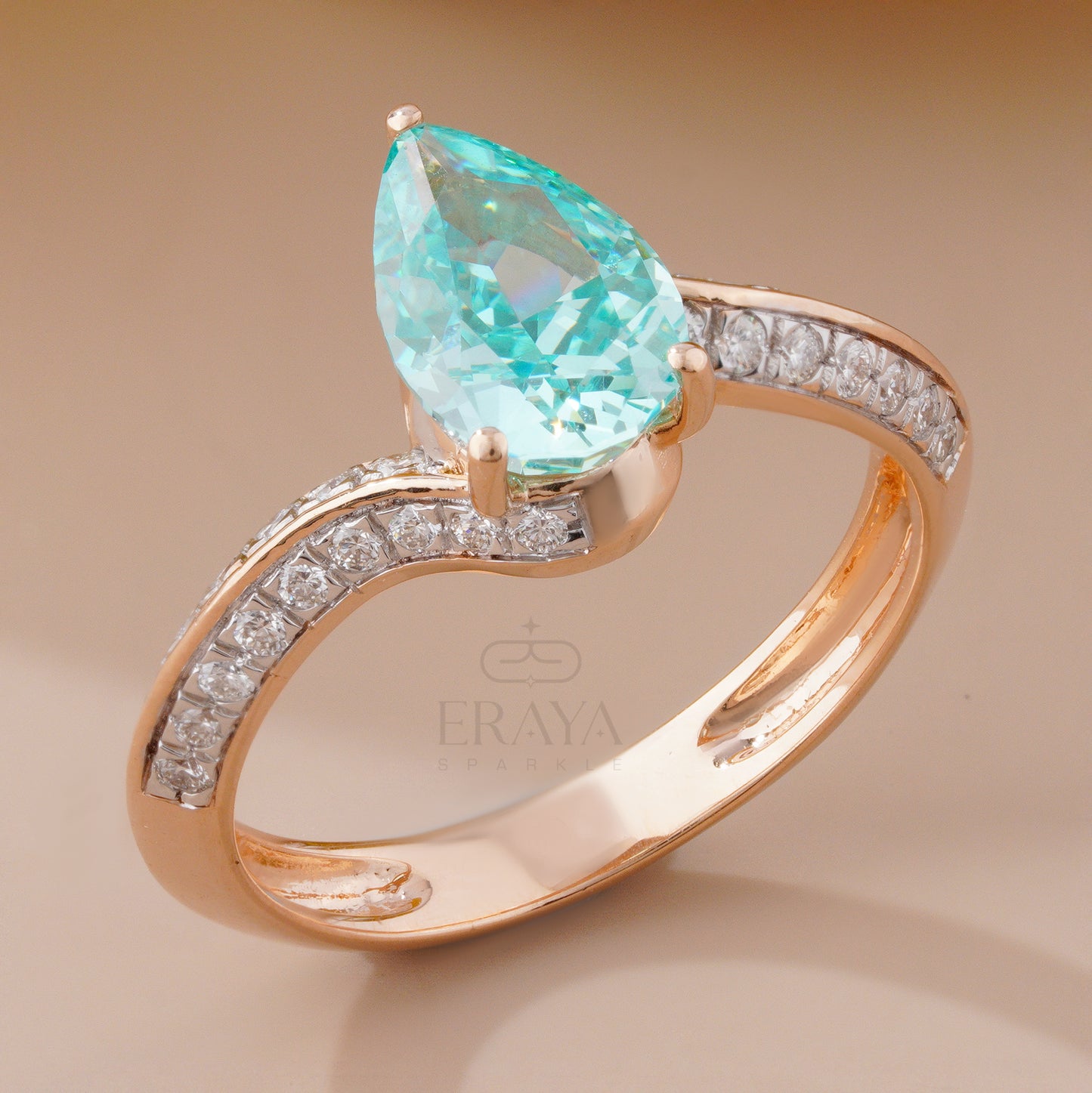 Rose gold ring with a pear-shaped green gemstone and diamond accents on a beige background