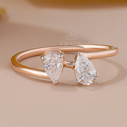 Rose gold ring with two pear-shaped diamonds on a beige background, featuring the brand 'Eraya'.