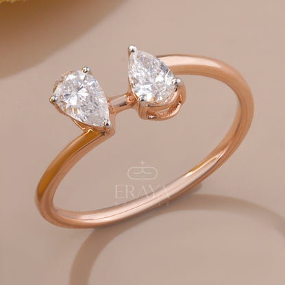 Rose gold ring with pear-shaped diamonds on a beige background