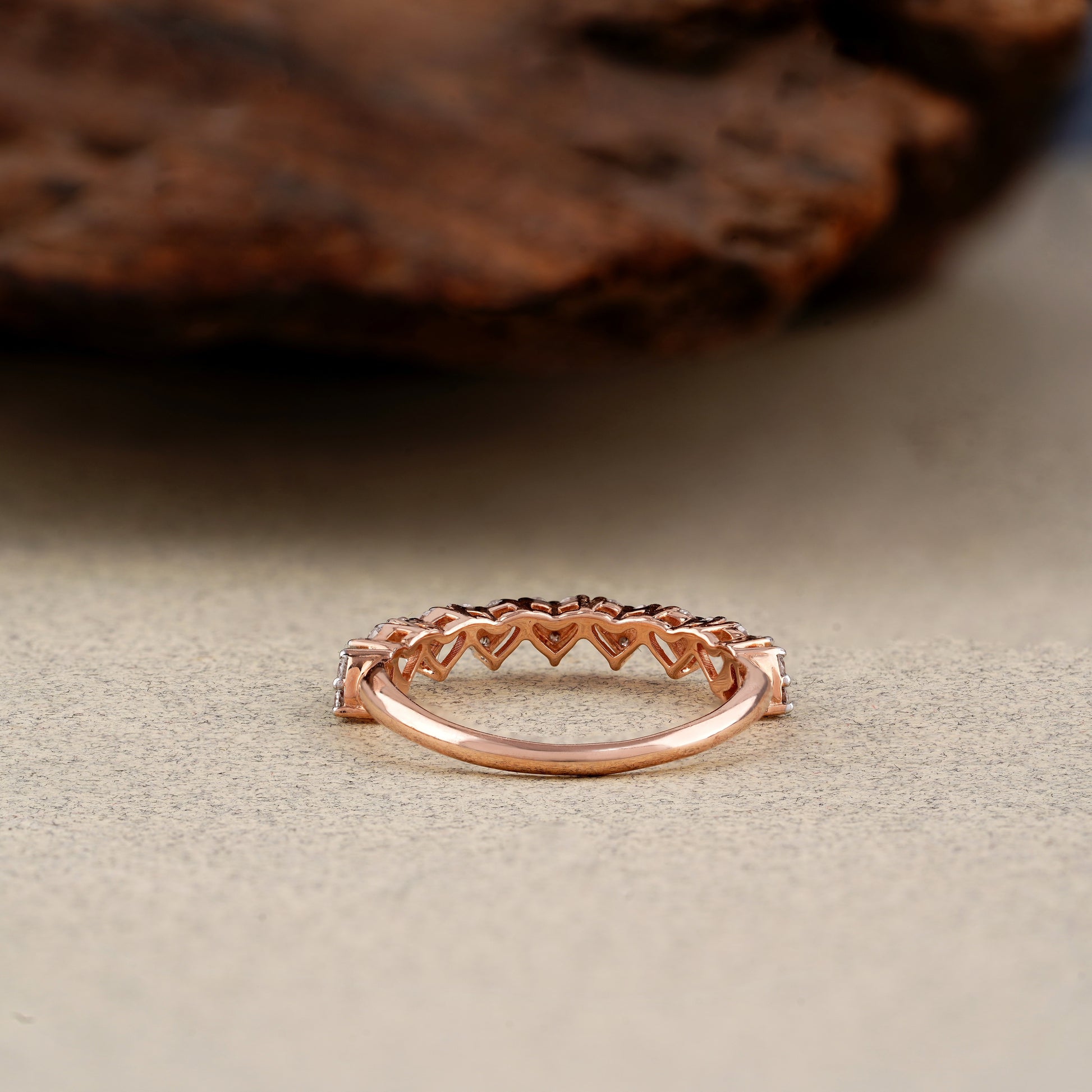 Rose gold ring with heart-shaped design on a textured surface