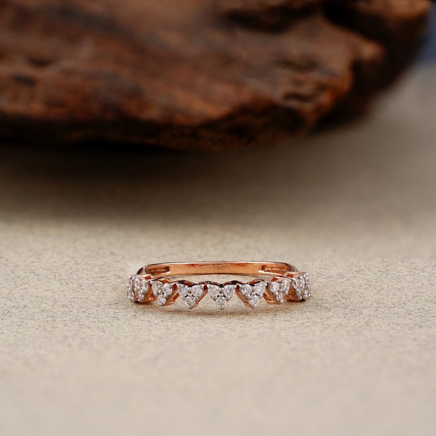 Rose gold ring with diamonds on a textured surface