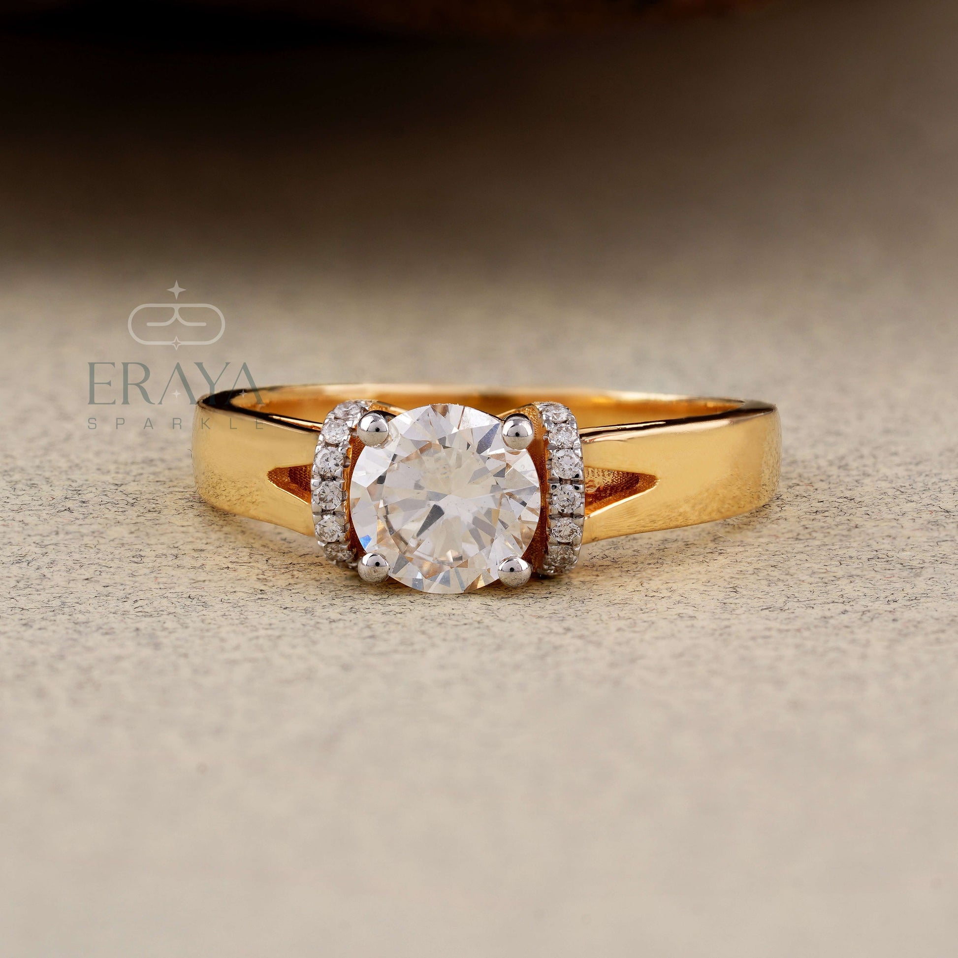 Gold ring with a diamond on a textured beige surface, featuring the brand 'Eraya'.