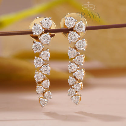 Gold earrings with clear gemstones on a blurred background, featuring the brand 'Eraya'.