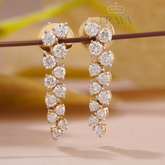 Gold earrings with clear gemstones on a blurred background, featuring the brand 'Eraya'.