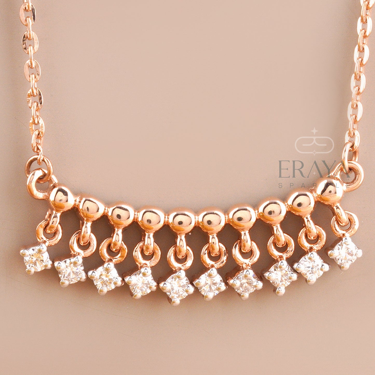 Close-up of dangling diamond charms on polished rose gold bar – lab grown diamonds IGI certified