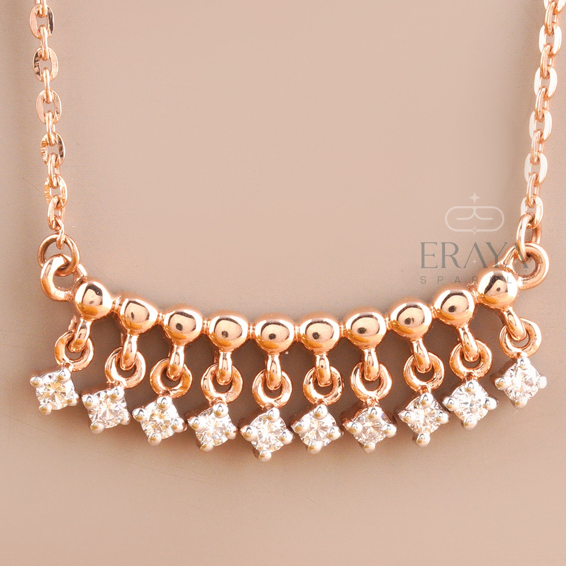 Close-up of dangling diamond charms on polished rose gold bar – lab grown diamonds IGI certified