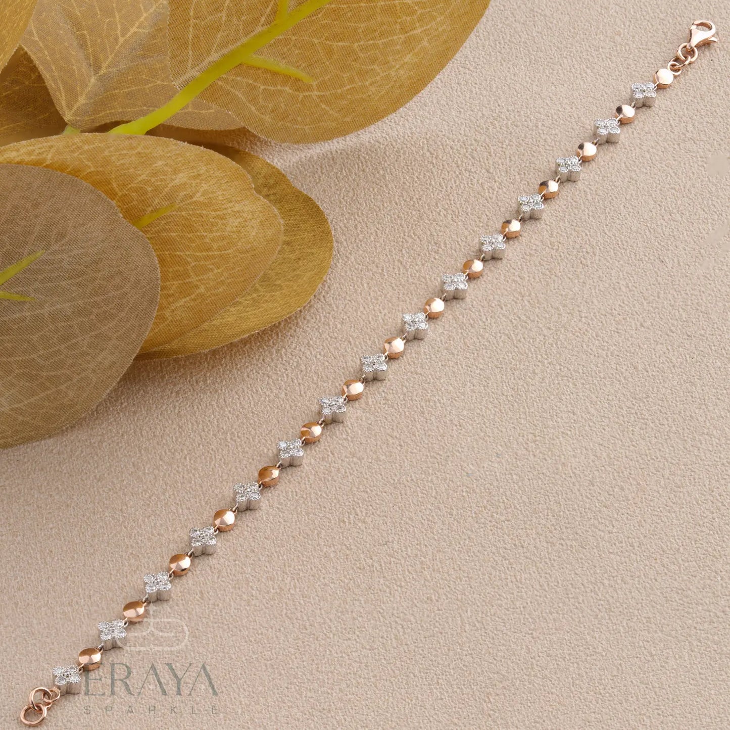 Delicate bracelet with rose gold and silver beads on a beige surface with leaves.