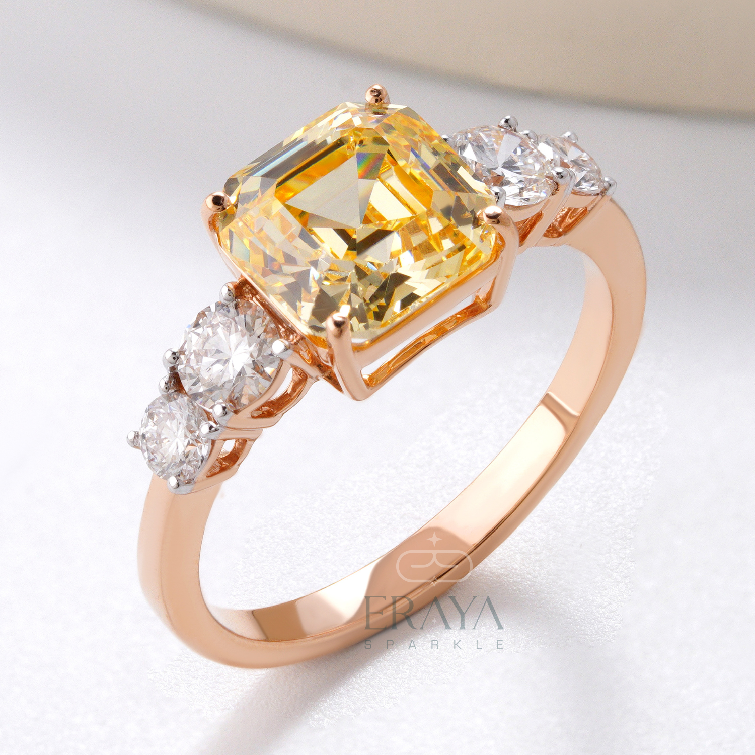 Rose gold ring with a yellow gemstone and smaller diamonds on a light background