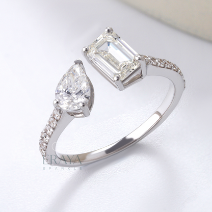 Diamond ring with pear-shaped and emerald-cut diamonds on a light background