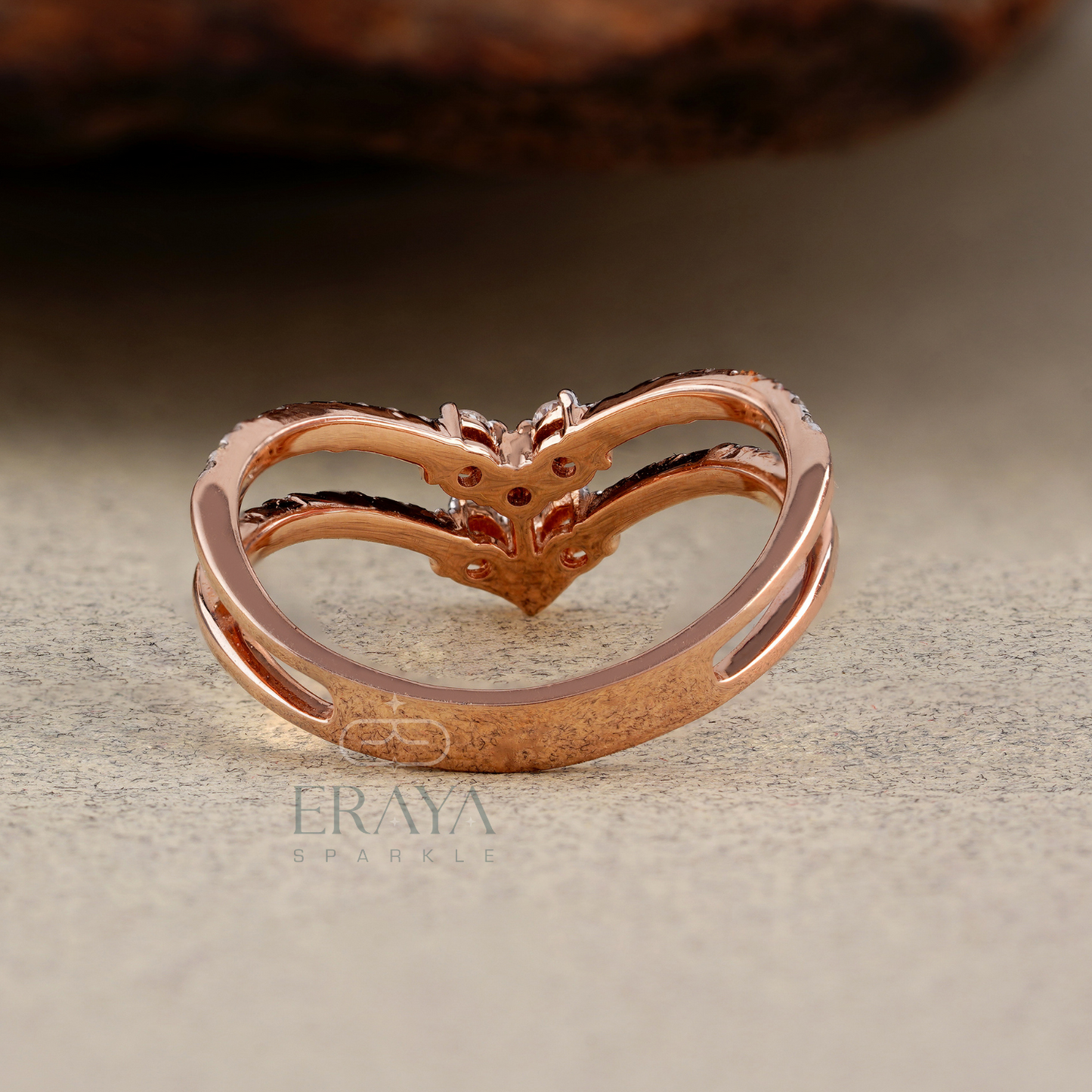 Rose gold heart-shaped ring on a textured surface with 'Eraya' branding.