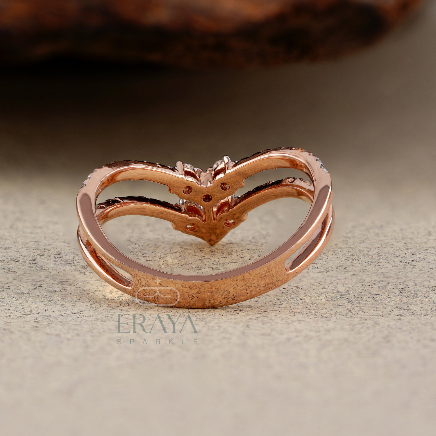Rose gold heart-shaped ring on a textured surface with 'Eraya' branding.